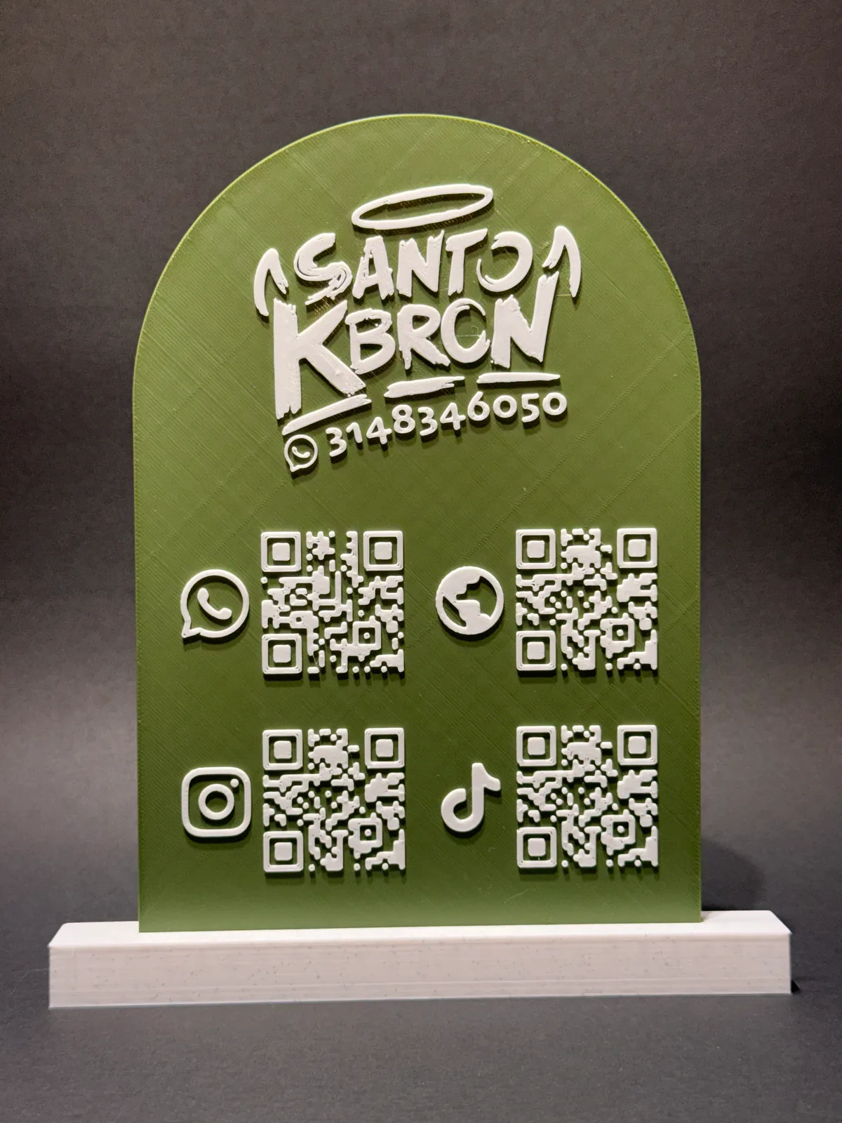 Placa QR con base verde de una sola pieza de frente, con el logo del negocio en relieve blanco arriba y cuatro códigos QR de redes sociales abajo — Solid Lab 3D, Colombia