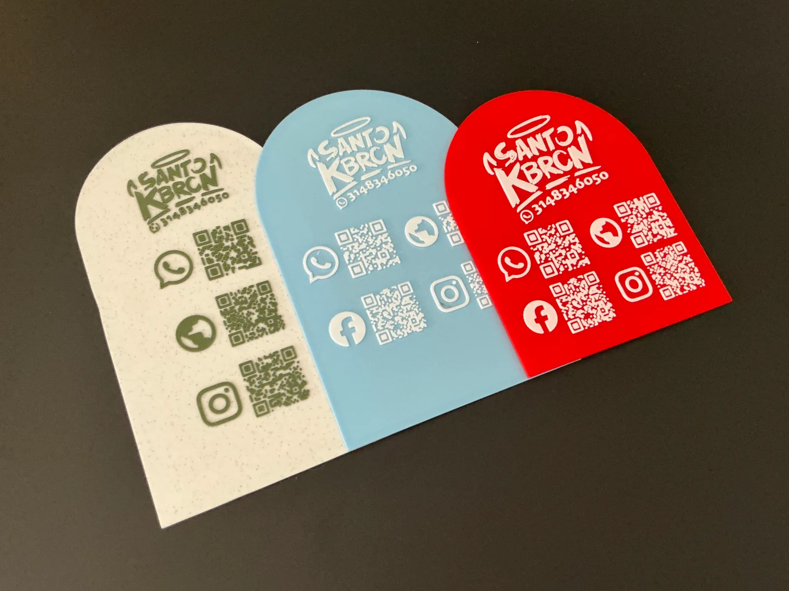 Tres Placas Portátiles QR abiertas en abanico en crema, azul claro y roja, para comparar de un vistazo cómo se ve el mismo diseño en cada color — Placa Portátil QR de Solid Lab 3D, Colombia