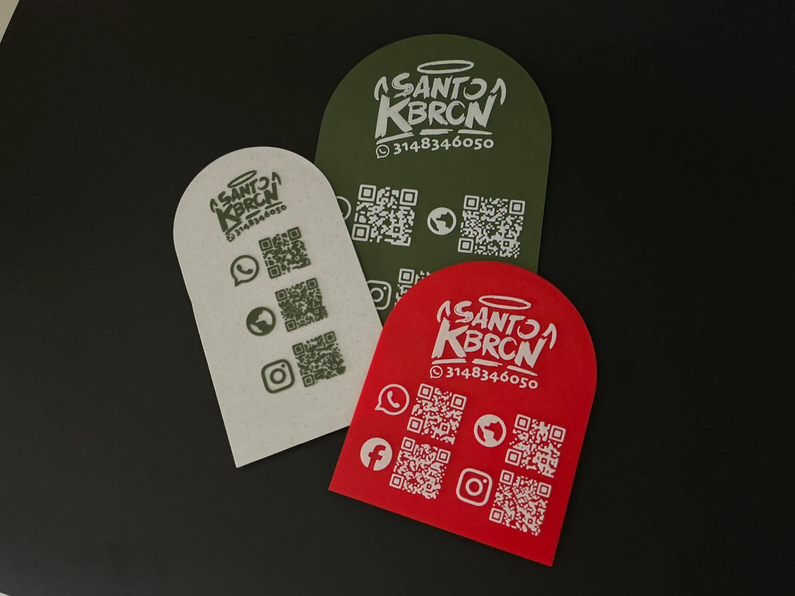 Tres Placas Portátiles QR repartidas sobre fondo negro en crema, verde oliva y roja, para comparar el contraste del relieve en un color claro y en dos oscuros — Placa Portátil QR de Solid Lab 3D, Colombia