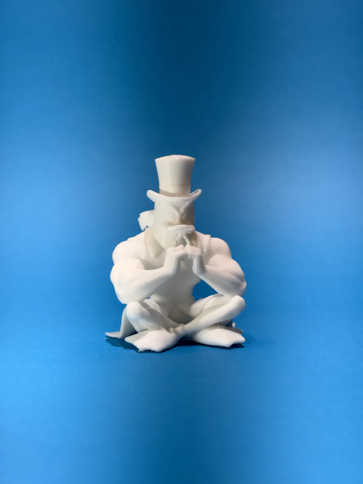 Figura temática de un personaje sentado con sombrero de copa en blanco sobre fondo azul, vista completa desde un poco más lejos y con el sombrero recto — Llaveros e imanes de Solid Lab 3D, Colombia