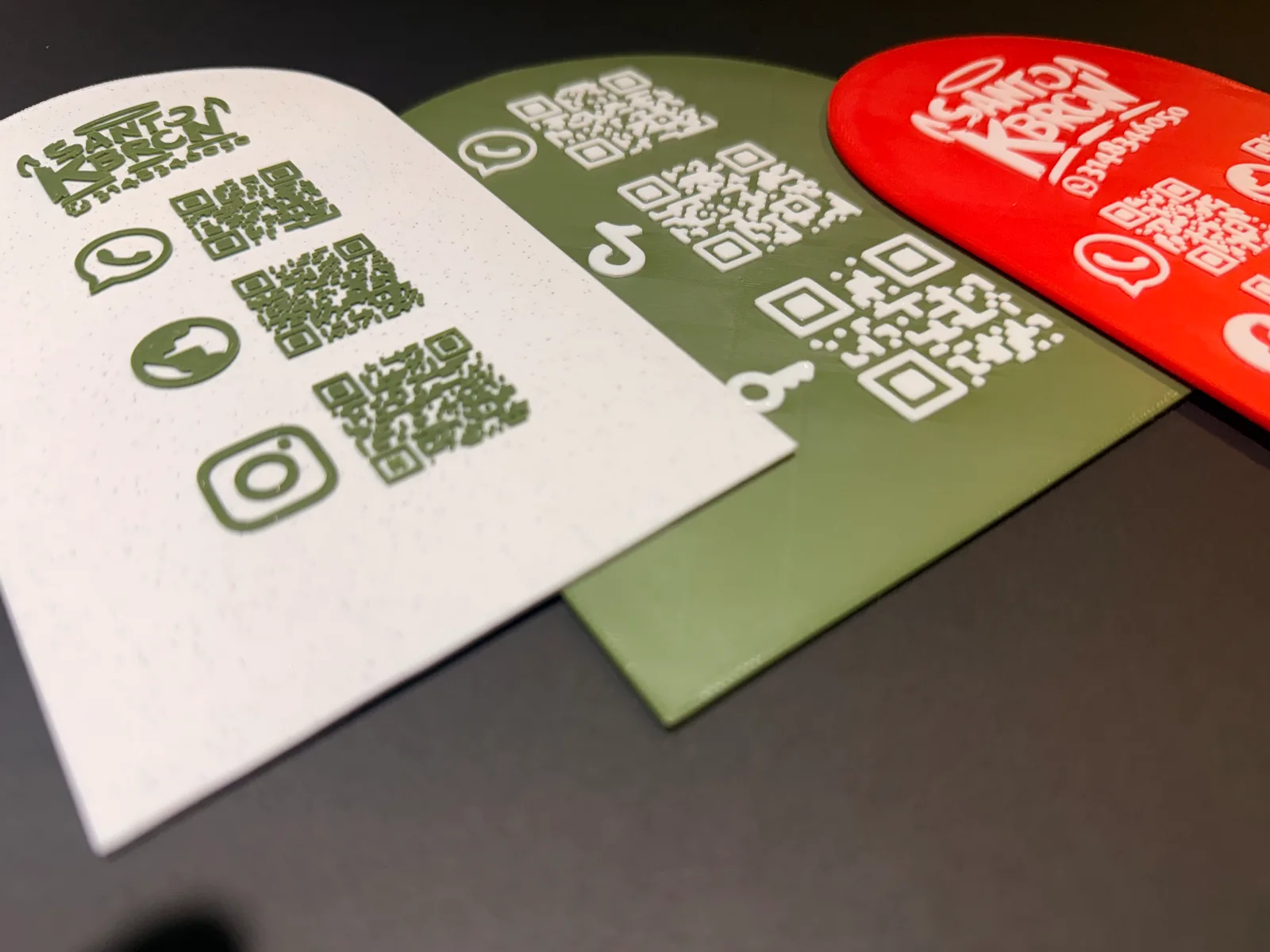 Tres Placas Portátiles QR en primer plano sobre una mesa oscura tal como quedan cuando el mesero las lleva a la mesa para que el cliente escanee el código — Placa Portátil QR de Solid Lab 3D, Colombia