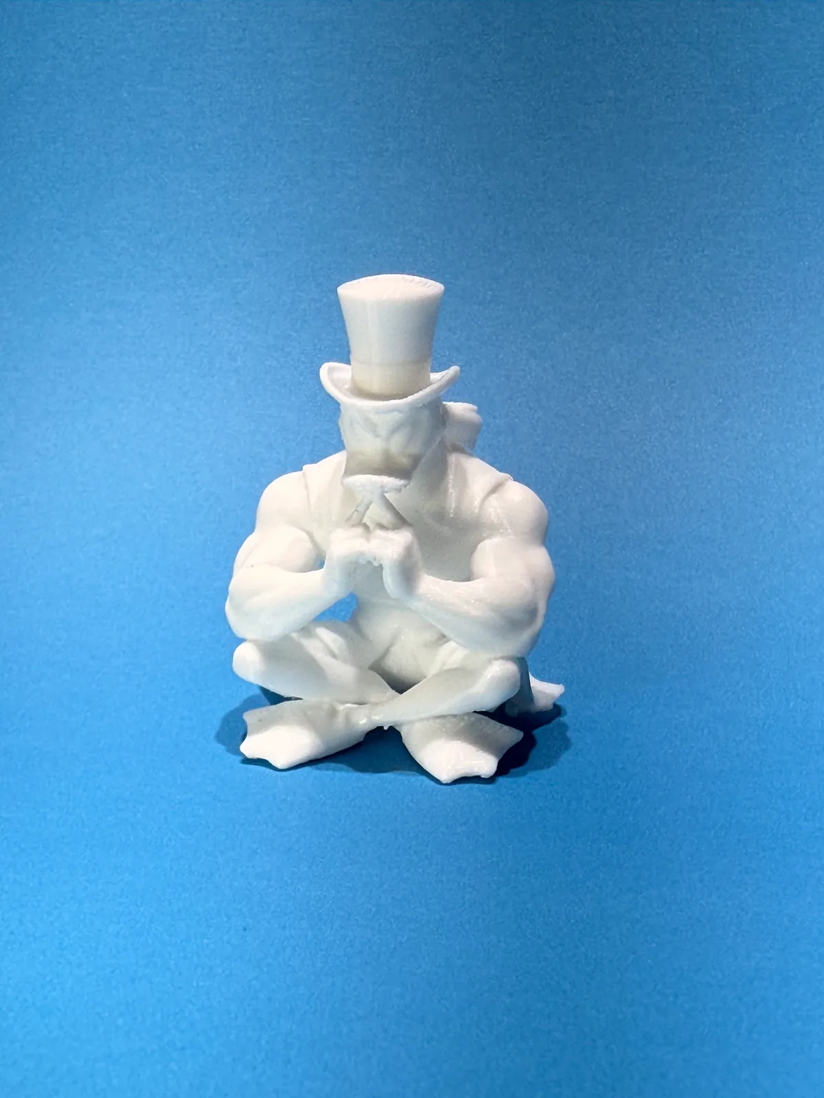 Figura temática de un personaje sentado con sombrero de copa en primer plano sobre fondo azul, donde se aprecian los pliegues de la ropa y los brazos capa por capa — Llaveros e imanes de Solid Lab 3D, Colombia