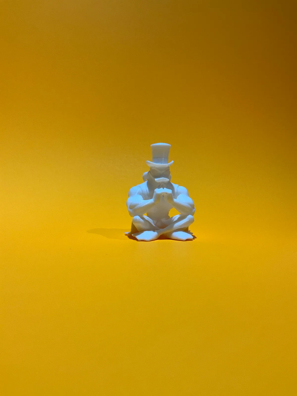 Figura temática de un personaje sentado con sombrero de copa sobre fondo amarillo y con luz lateral, que deja ver lo fino del relieve en una pieza pequeña — Llaveros e imanes de Solid Lab 3D, Colombia